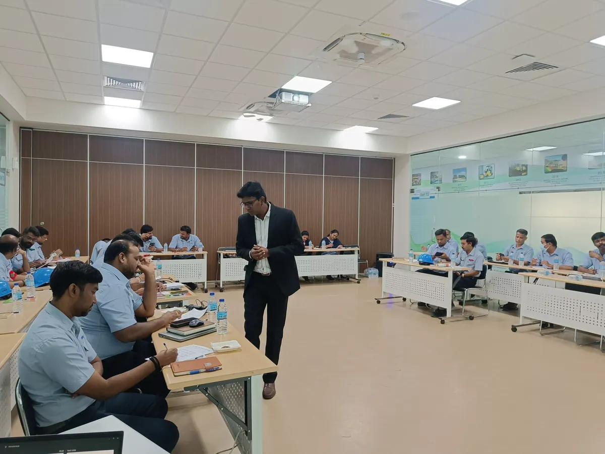 A training room mid-session, participants seated at desks while the facilitator moves between them